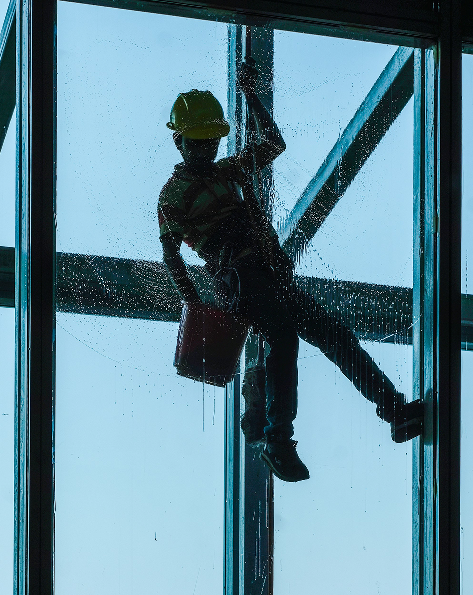 Window cleaner washing exterior glass on a brick building
